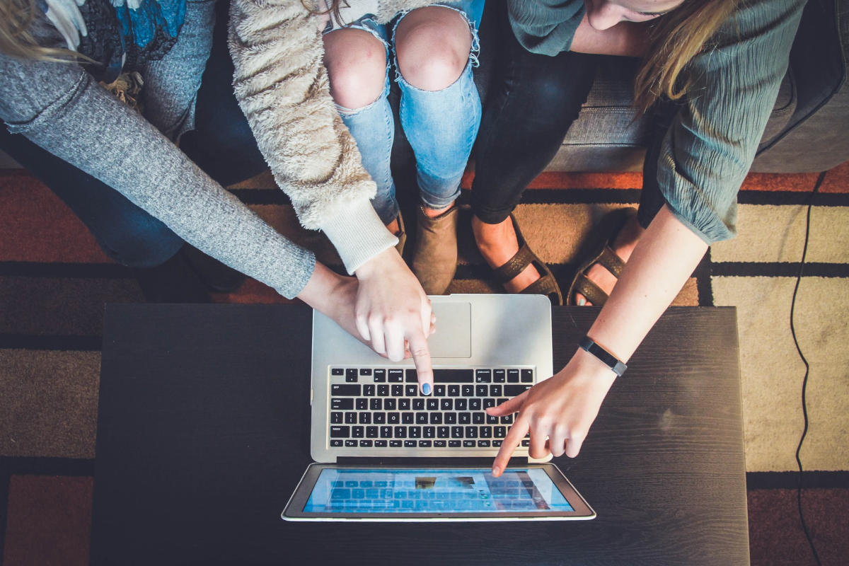 Drei Personen zeigen auf einen Laptop