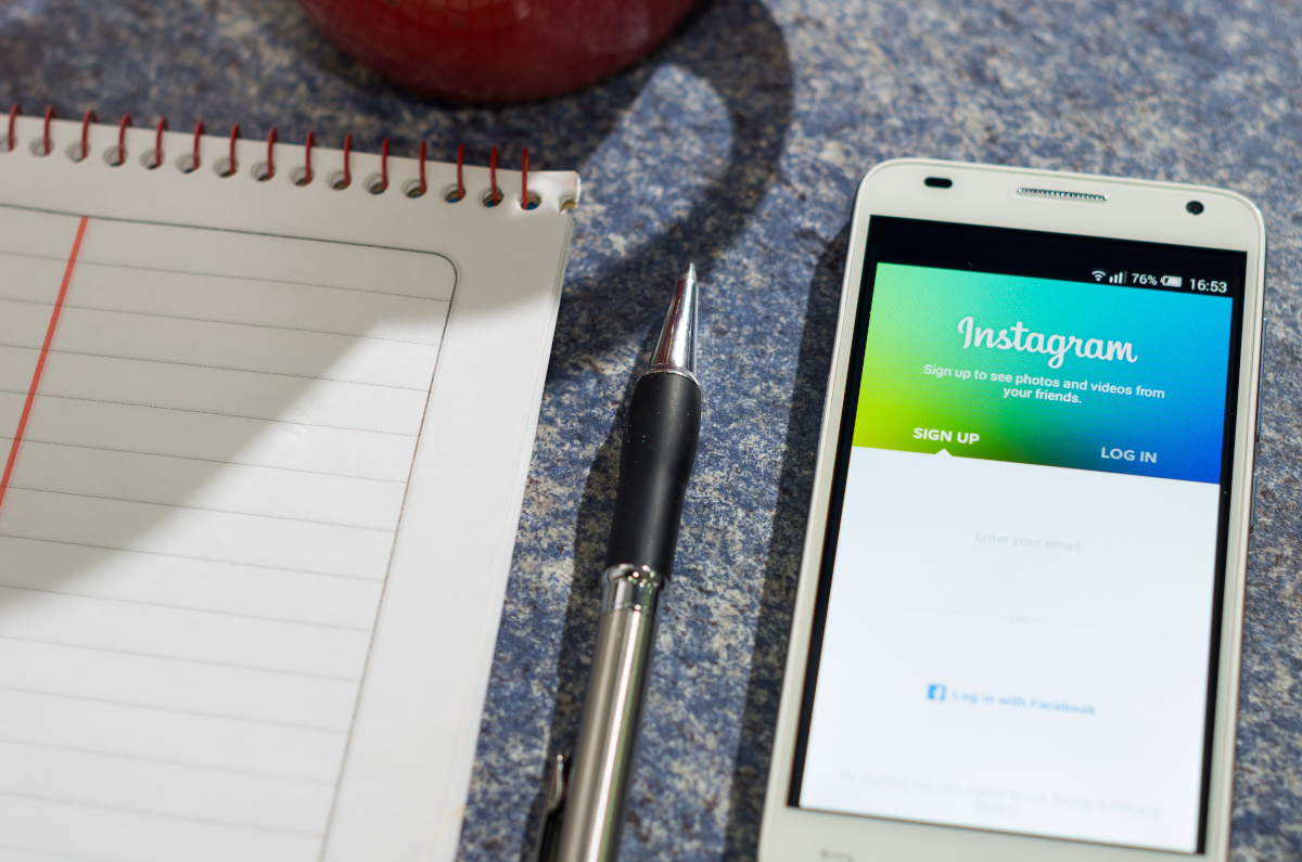 Neben einem Notizblock liegt ein Smartphone, das die Anmeldeseite von Instagram zeigt