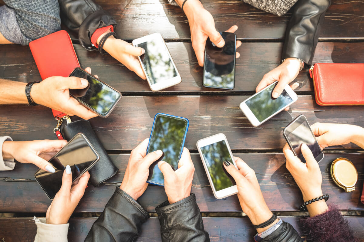 Eine Gruppe von jungen Personen, die ihre Smartphones in der Hand haben.